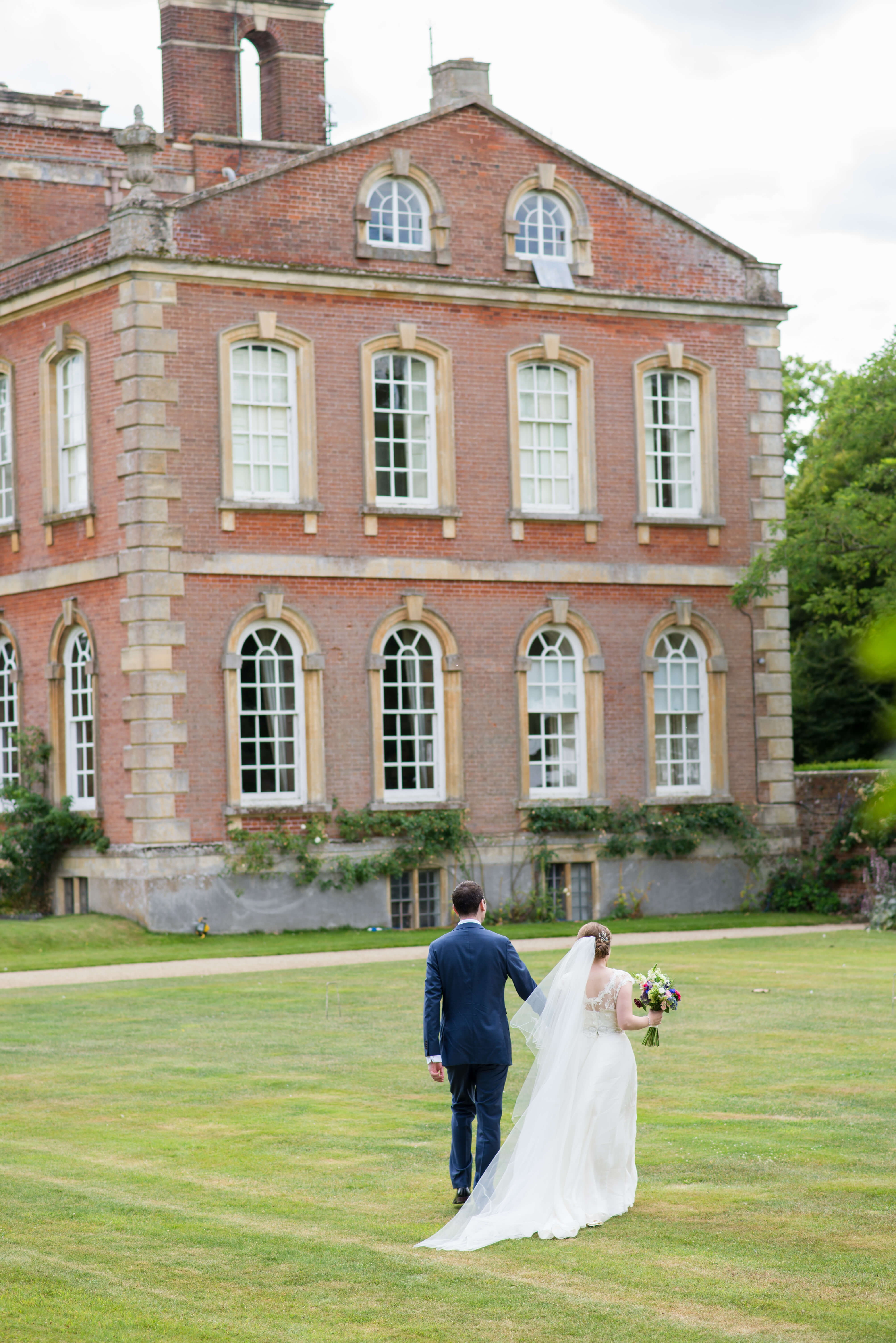 A bride and groom walking in the gardens of Kingston Bagpuize House in Oxfordshire